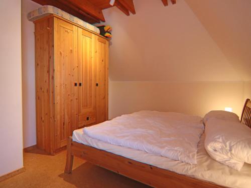 a bedroom with a bed and a wooden cabinet at Reihenhaus Dünenwaldhaus in Trassenheide in Trassenheide