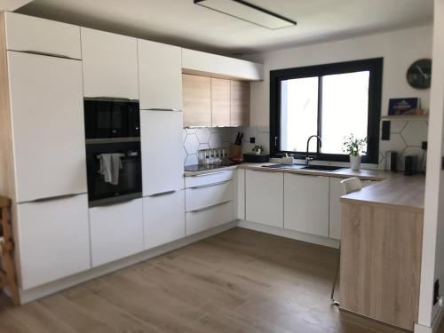 une cuisine avec des placards blancs et une grande fenêtre dans l'établissement Villa Larmor-Plage 8 personnes avec piscine, à Larmor-Plage