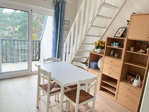 - une table et des chaises blanches dans une chambre avec des escaliers dans l'établissement Logement cosy proche de la mer, à Houlgate