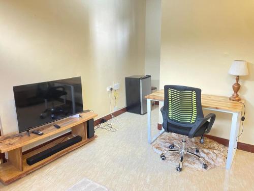 a room with a desk and a chair and a television at city zeze kinondoni in Dar es Salaam