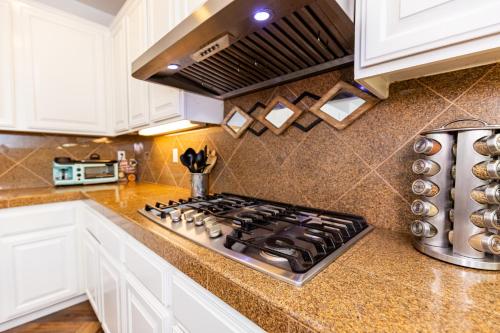 a kitchen with white cabinets and a stove top oven at Vineyard estate with pool and amazing views in Yucaipa