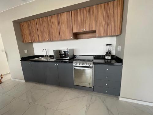 a kitchen with a sink and a stove and cabinets at Departamento Perla Ngra a pasos del Mar in Boca del Río