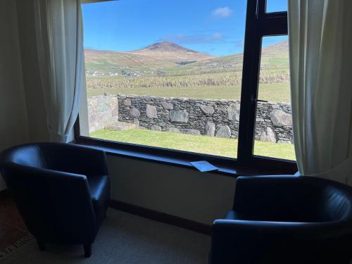 a room with two chairs and a window with a view at Barr na hAille in Dunquin