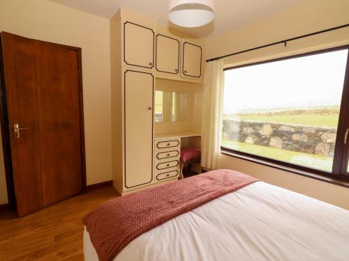 a bedroom with a bed and a large window at Barr na hAille in Dunquin
