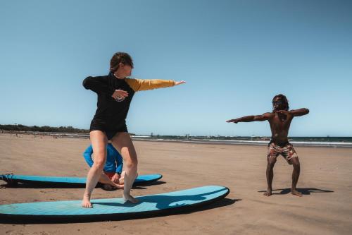 two people standing on surfboards on the beach at Iguana Surf Camp in Tamarindo