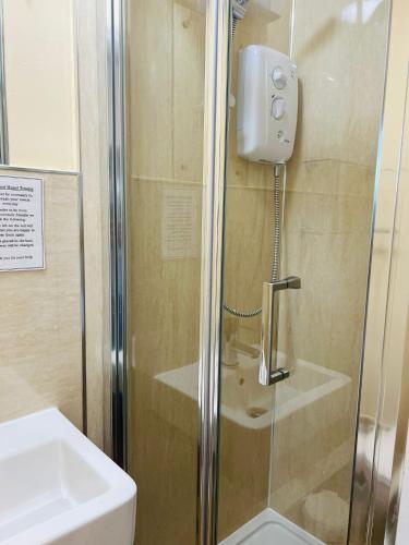 a shower with a glass door next to a sink at Rothwell House Hotel in Kettering