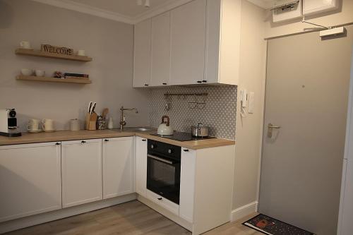 a kitchen with white cabinets and a stove top oven at Apartament w Sosnowym SPA in Serock