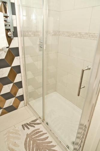 a shower with a glass door in a bathroom at Together in Ealing, Modern Two Bedroom Flat with Garden, Patio, Parking and Sleeps Five in Ealing