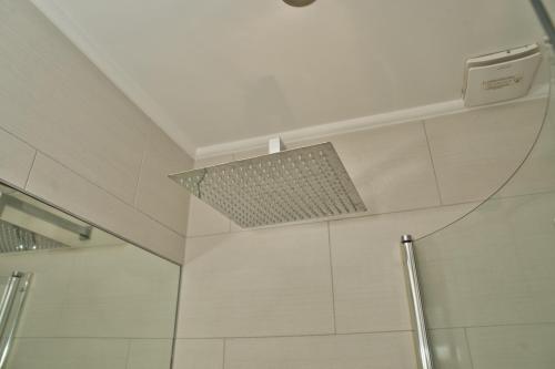 a shower in a bathroom with a light on the ceiling at Together in Ealing, Modern Two Bedroom Flat with Garden, Patio, Parking and Sleeps Five in Ealing