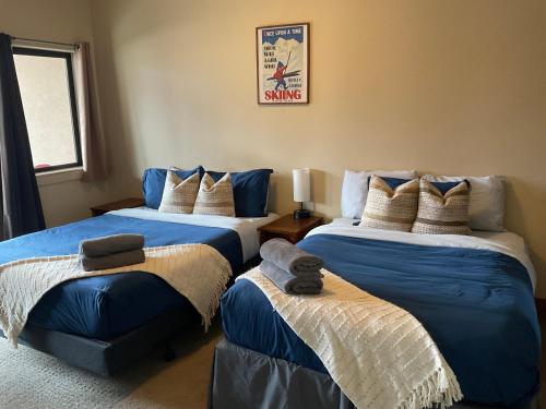 a bedroom with two beds with blue and white sheets at Lily glacier suite at silver bear condos in Revelstoke