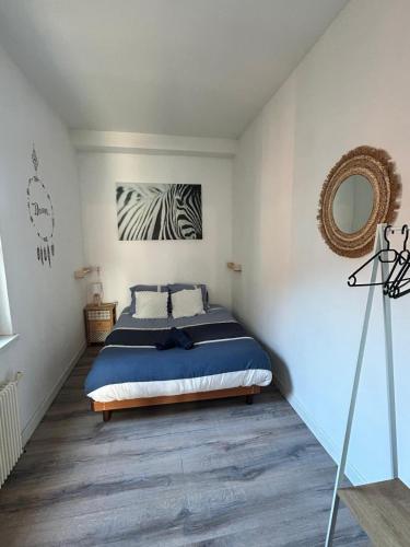 une chambre avec un lit et un miroir au mur dans l'établissement Appartement F2 meublé, à Dunkerque
