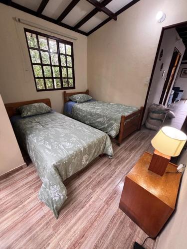 a bedroom with two beds and a table and a window at Casa Bella Campestre in Guayabal de Síquima