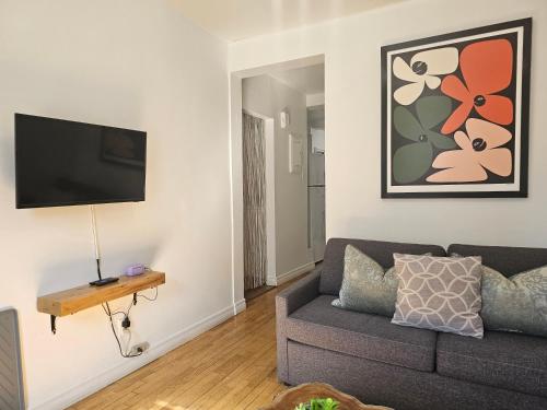 a living room with a couch and a flat screen tv at Espace Couronne by Hébergements DCL in Quebec City