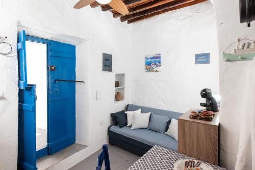 a living room with a blue couch and a blue door at Kimolos Heart Traditional Renovated House in Kimolos