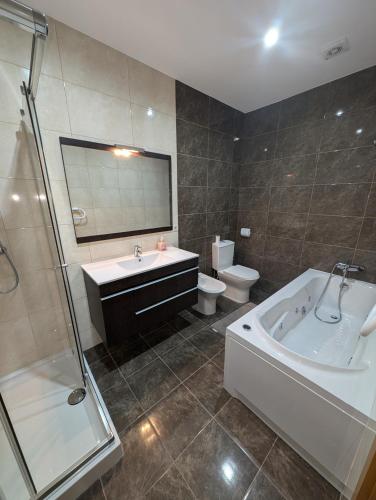 a bathroom with a tub and a sink and a toilet at Apartamento Sol e Mar in Fão