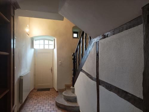 un couloir avec des escaliers et une porte avec une fenêtre dans l'établissement Gite ancien presbytère, à Barrais-Bussolles