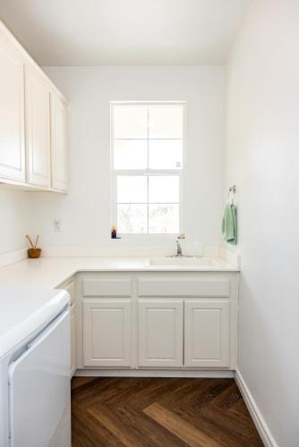a white kitchen with a sink and a window at Vineyard estate with pool and amazing views in Yucaipa