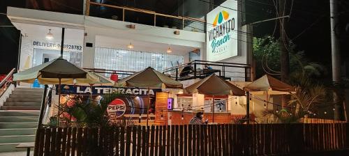 a building with tables and umbrellas in front of it at Prim Hotel Vichayito in Vichayito