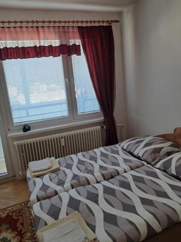 a bed in a bedroom with a large window at Spacious flat in Prievidza near Bojnice with a beautiful view in Prievidza