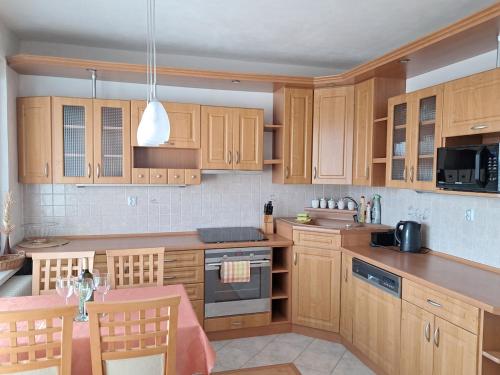 a kitchen with wooden cabinets and a table with chairs at Spacious flat in Prievidza near Bojnice with a beautiful view in Prievidza