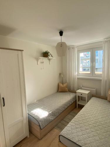 a small bedroom with two beds and a window at Apartament Promyk in Świnoujście