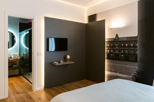 a bedroom with a bed and a tv on a wall at NILO RELAIS a san domenico maggiore in Naples