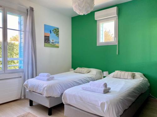 - 2 lits dans une chambre dotée de murs verts et de fenêtres dans l'établissement Joli appartement proche mer, à Saint-Gilles-Croix-de-Vie