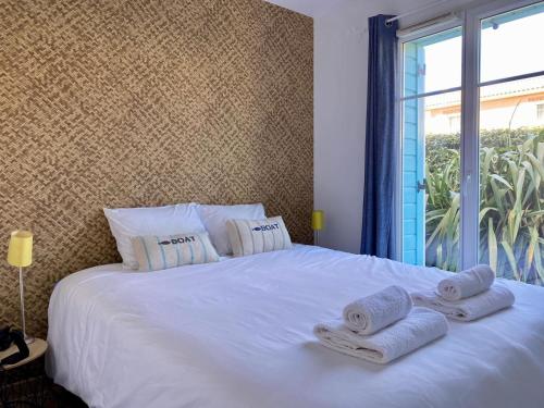 une chambre avec un lit blanc avec des serviettes dessus dans l'établissement Joli appartement proche mer, à Saint-Gilles-Croix-de-Vie
