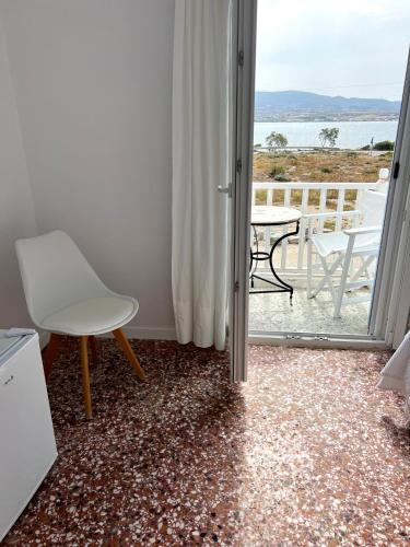 a room with a white chair and a table and a balcony at Windmill Rooms in Antiparos Town