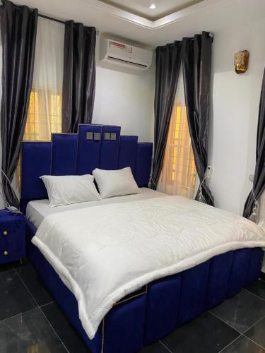 a blue bed in a room with two windows at Grand Island Apartment 1 in Abuja