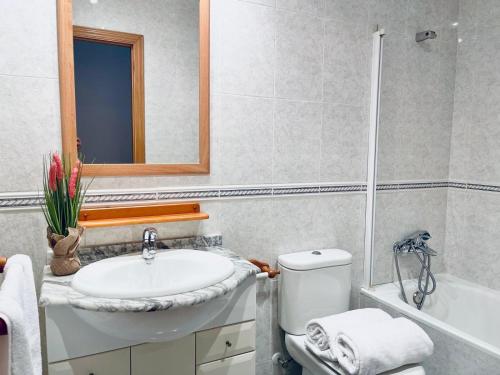a bathroom with a sink and a toilet and a mirror at Planta baja en pleno centro de la playa in Moncófar