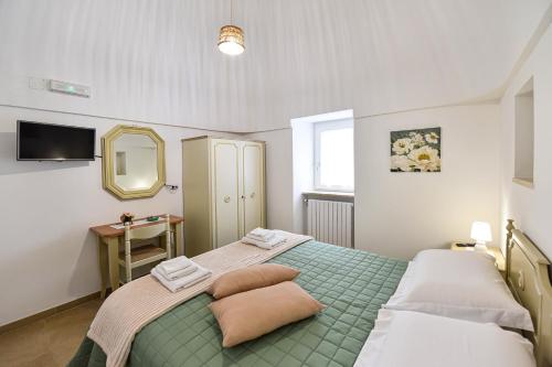 a bedroom with a green bed and a mirror at La Dimora di Peppe in Locorotondo