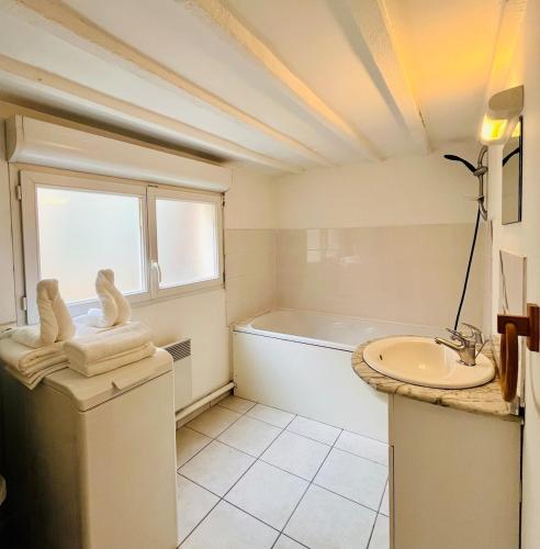 une salle de bain blanche avec une baignoire et un lavabo dans l'établissement Logement charmant cosy central, à Caen