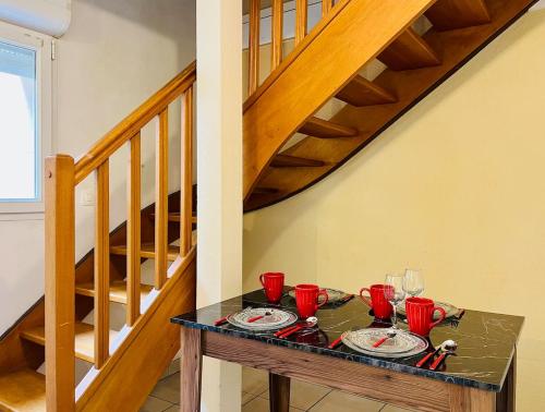 une table avec des tasses et des assiettes rouges sur une table sous les escaliers dans l'établissement Logement charmant cosy central, à Caen