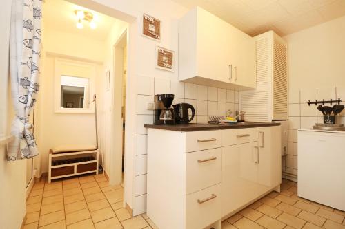 a kitchen with white cabinets and a tile floor at Strandkojen in Trassenheide