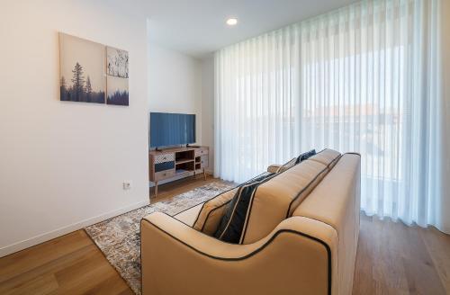 a living room with a couch and a tv at Tiles 23 Luxury Apartment & Parking by Home Sweet Home Aveiro in Aveiro