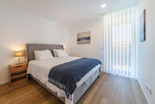 a bedroom with a bed and a large window at Tiles 23 Luxury Apartment & Parking by Home Sweet Home Aveiro in Aveiro