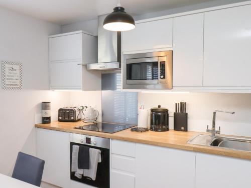 a kitchen with white cabinets and a sink at Denby Escape in Filey