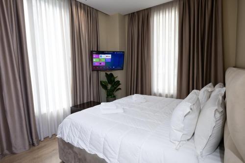 a hotel room with a white bed and a flat screen tv at 4R Colombo Hotel in Tirana