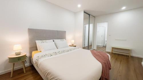 a white bedroom with a large bed and two lamps at Nico Home in Ponta Delgada