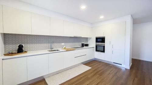 a white kitchen with white cabinets and a wooden floor at Nico Home in Ponta Delgada