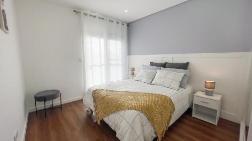 a white bedroom with a bed and a chair at Nico Home in Ponta Delgada