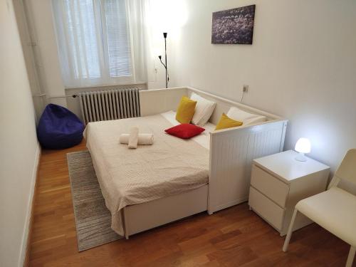 Cette petite chambre comprend un lit avec des oreillers rouges et jaunes. dans l'établissement Mia City Center - Apartment Belgrade, à Belgrade