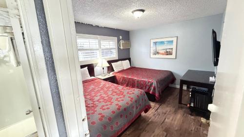 a hotel room with two beds and a desk and a window at Fireside Inn By The Beach Boardwalk & Bowling in Santa Cruz