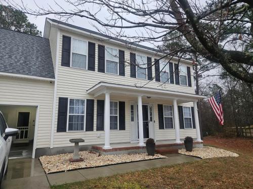a white house with an american flag in front of it at Spacious 3 BR Retreat in Leland in Leland