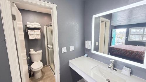 a bathroom with a sink and a toilet and a mirror at Fireside Inn By The Beach Boardwalk & Bowling in Santa Cruz