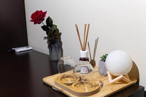 a wooden tray with a bottle of perfume and a red rose at 4R Colombo Hotel in Tirana