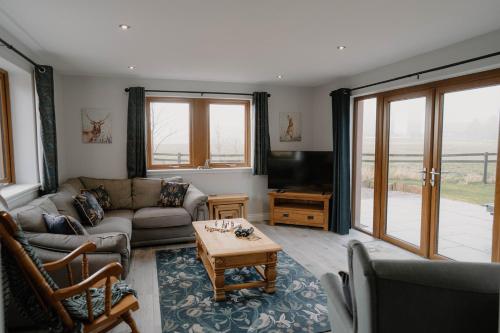 a living room with a couch and a table at Stanloch Farmhouse - well equipped, games room, EV in Glencaple