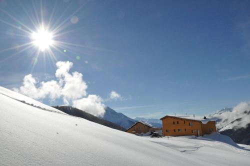 a building on a snow covered slope with the sun at Berghotel Chäserstatt in Ernen