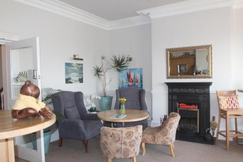 a living room with a table and chairs and a fireplace at Bryn-Y-Mor Hotel in Llandudno